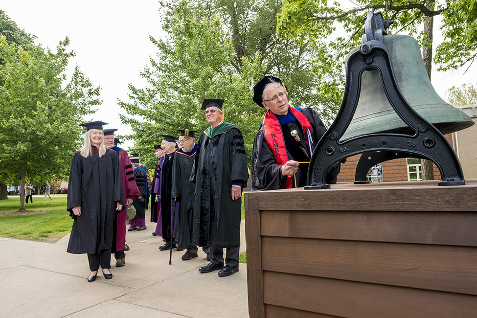Jack Mutti, College marshal, rings the College bell to start the processional.