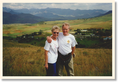 George and Sue stand arm in arm against a backdrop of meadows farms and mountains