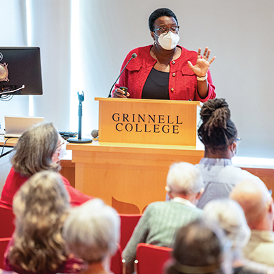 Beronda Montgomery in a face mask at a Grinnell College lecture speaking to an audience