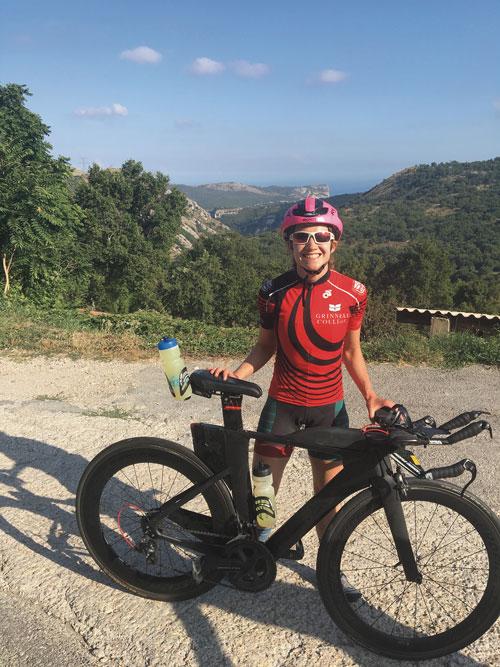Maddy Pesch in Grinnell riding gear with her bike on a mountain pass