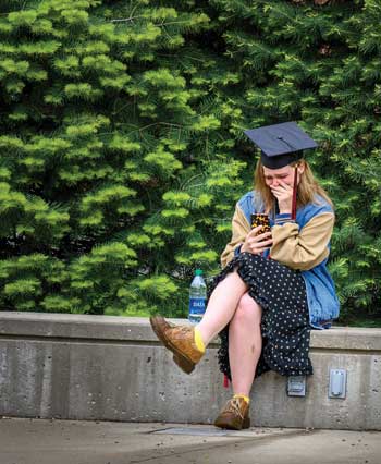A student wearing her mortar board cap watched her virtual Commencement on campus at the empty stage.