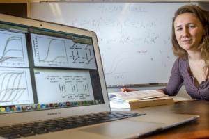 Josie Bircher sits at a laptop and shows data models on a display screen
