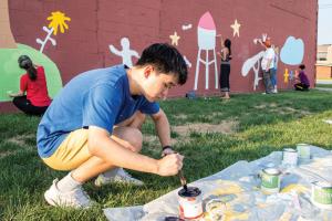 Tommy Lee ë22 get paint ready for community members to paint on the mural design he created
