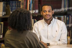 Jovan Johnson talks with student in library