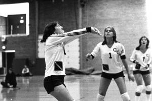 Black and white photo of three players, one with arms out to volley