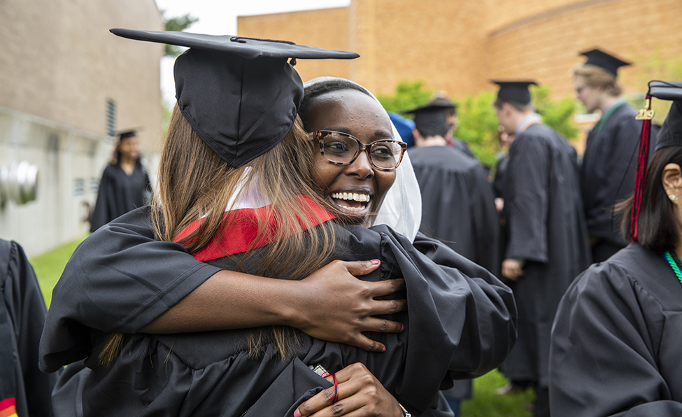 graduate hugging another graduate