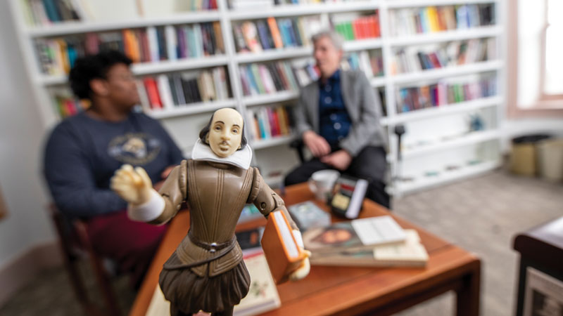 Shakespeare doll with Mellon fellow Elijah Griffin sharing his research with professor John Garrison in background