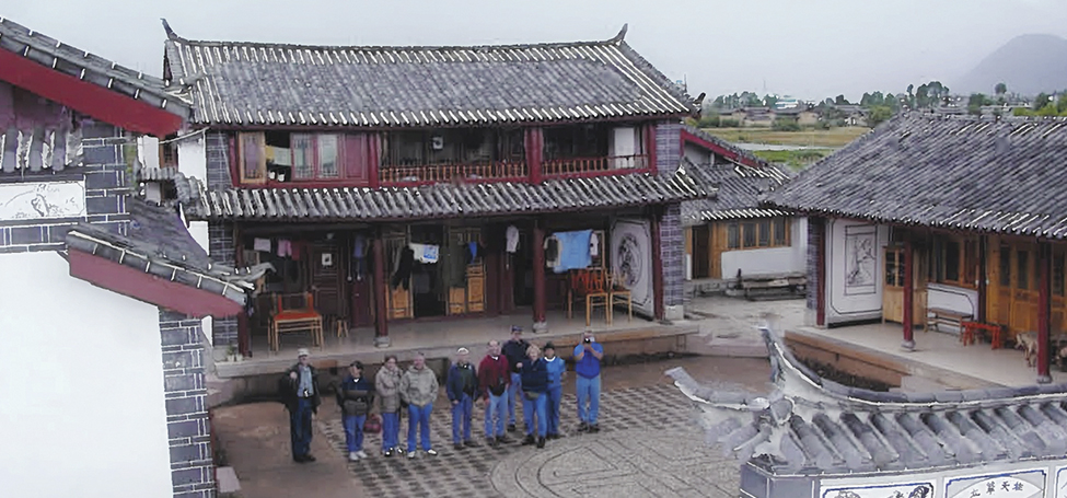 a group stands in the paved square between traditional Chinese buildings