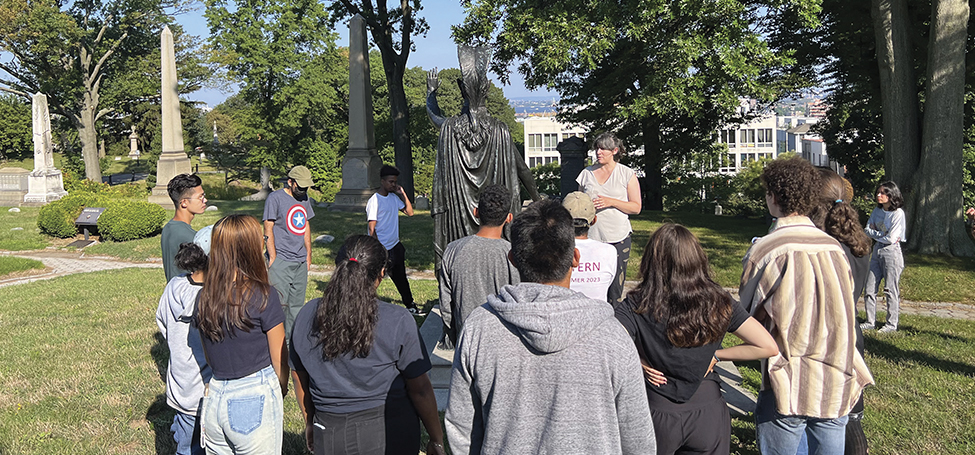 Rachel Walman talks to a group of people in front of a large monument