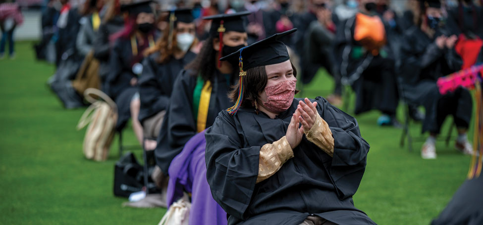 masked and gowned graduates celebrate commencement