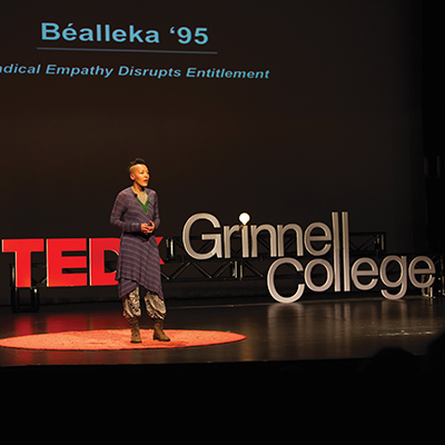 Speaker on stage with TEDx Grinnell College sign in the background