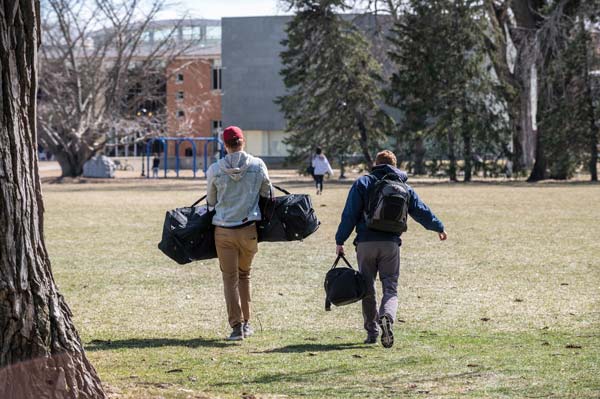 Everyone pitched in to help students depart safely. (People cross central campus laden with bags and backpacks)