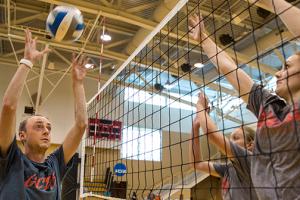 Eric Ragan sets a volleyball on the left side of the net to two women on the other side