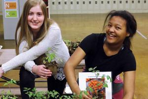 Two students with plants grown in greenhouse
