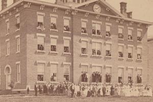 Students stand outside of campus building in 1879